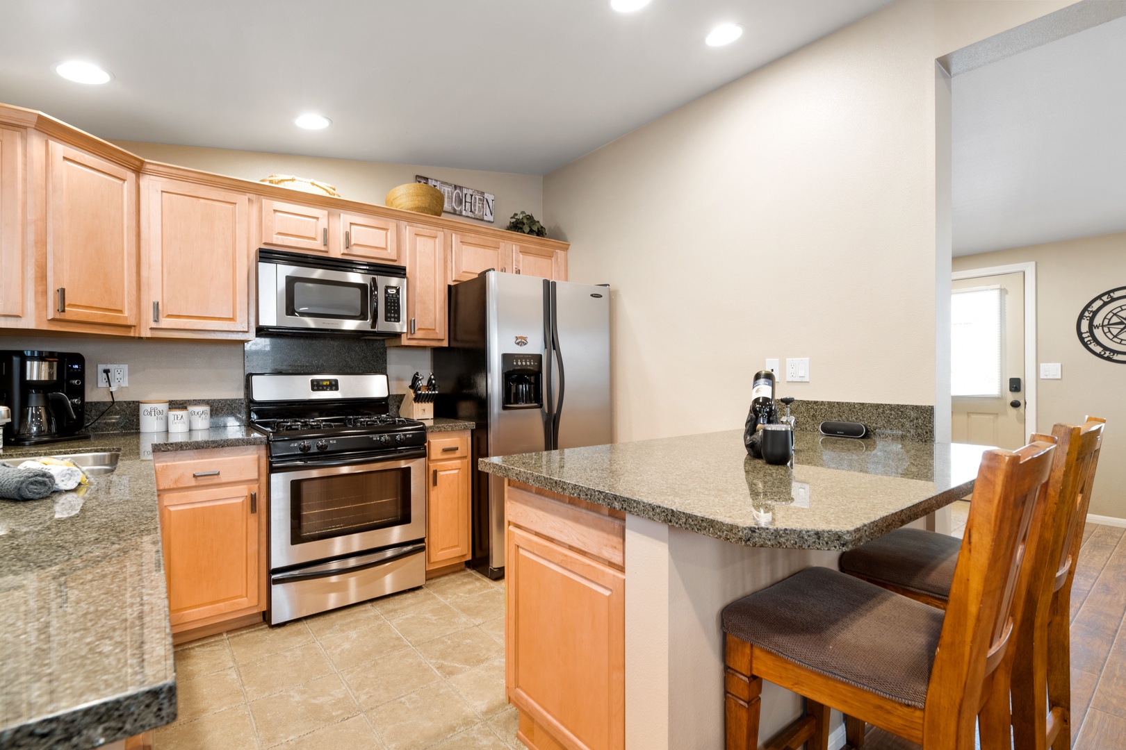 Your fully equipped kitchen awaits with modern stainless appliances, granite countertops, and a breakfast bar where you can gather for morning coffee or evening meals.
