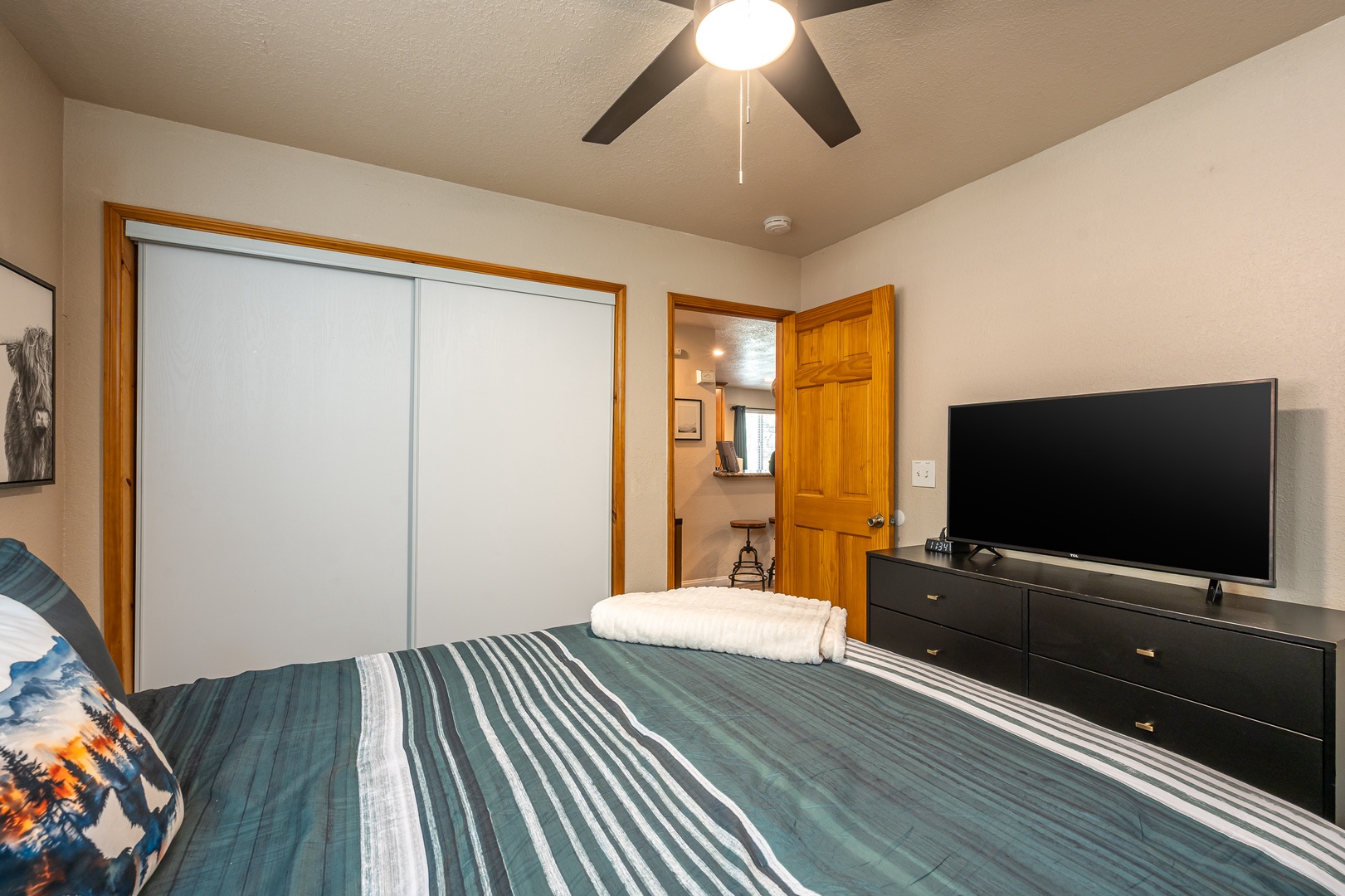 Your cozy bedroom features a plush bed dressed in crisp linens, a ceiling fan for comfort, ample closet space, a flat-screen TV for entertainment, and thoughtful touches to make you feel at home.