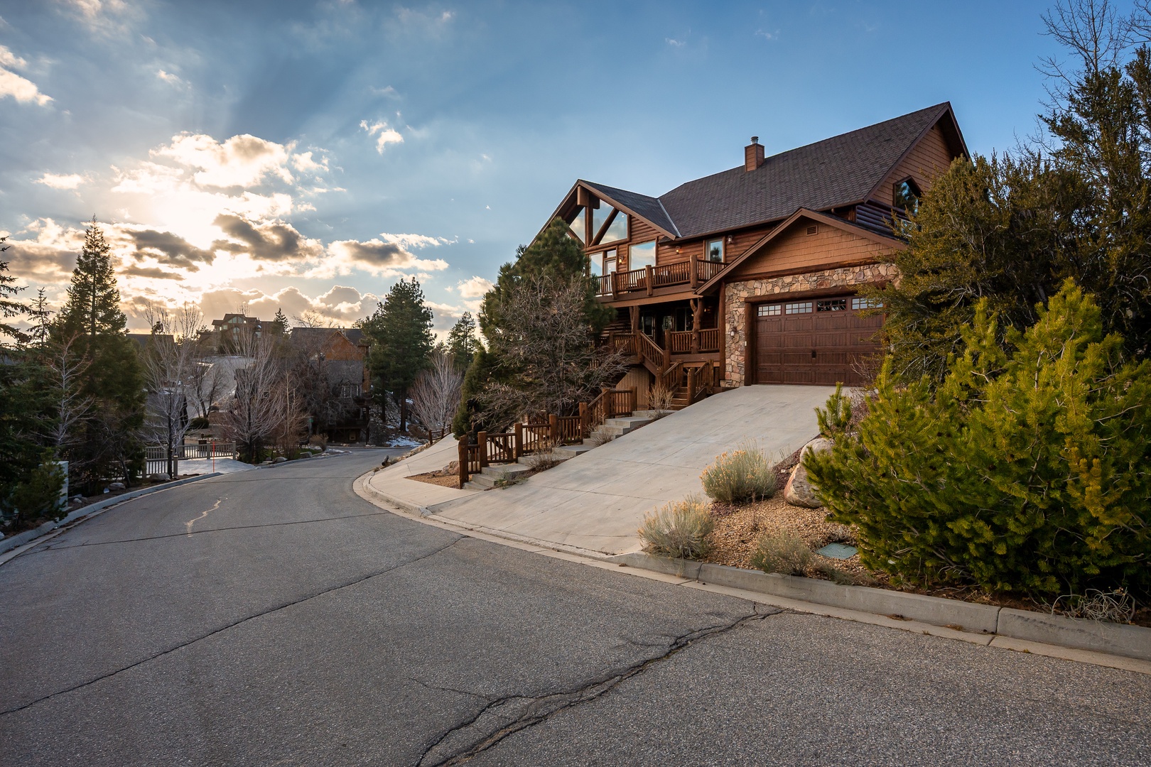 Impressive mountain lodge with stone and timber architecture nestled in a peaceful residential neighborhood, featuring scenic views and mature landscaping.