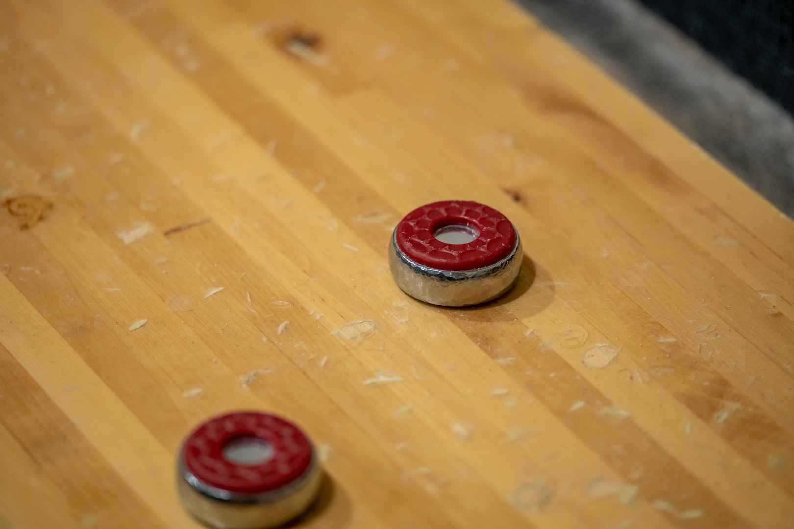 Shuffleboard gaming pieces rest on a polished wooden playing surface, ready for your next friendly competition or leisurely evening game.
