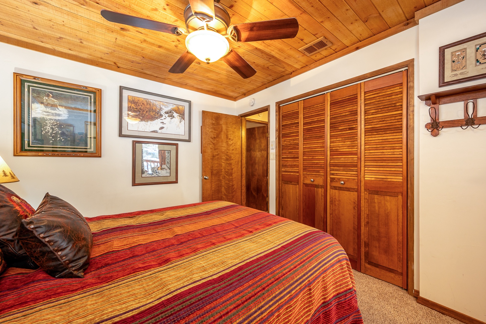Settle into this cozy bedroom where rustic wood paneling and a handcrafted ceiling fan create a warm, cabin-inspired retreat. Your clothes find a home in the spacious wooden wardrobe.