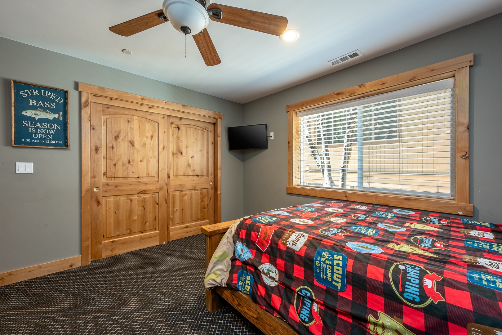 Your cozy bedroom features rustic wood accents, a ceiling fan for comfort, and a large window inviting natural light into your peaceful retreat.