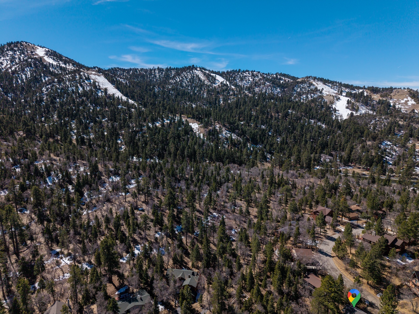 Stunning aerial view of the mountain community showcasing snow-capped peaks and forested terrain surrounding the neighborhood.