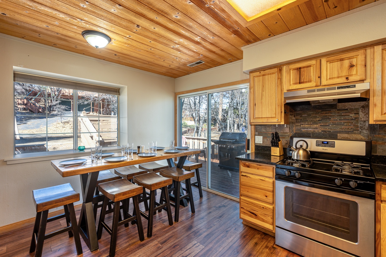 Gather around your rustic dining table where warm wood beams frame views of snow-dusted trees through expansive windows.