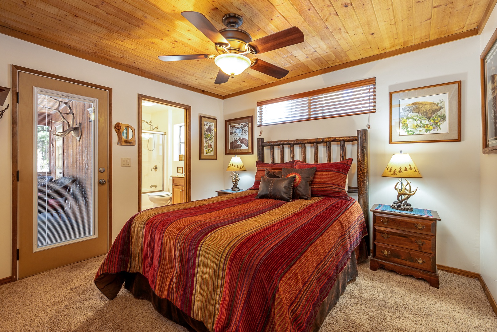 Unwind in your cozy retreat with rustic wood ceiling, vibrant bedding, and gentle ceiling fan creating perfect comfort.