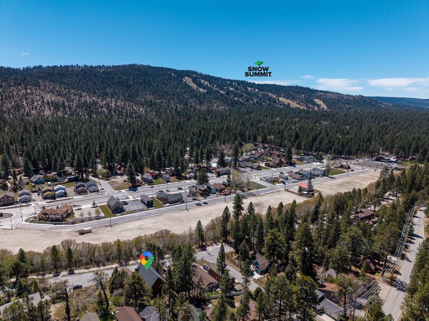 Aerial view of the surrounding mountain community, with Snow Summit ski resort visible on the wooded slopes above the neighborhood.