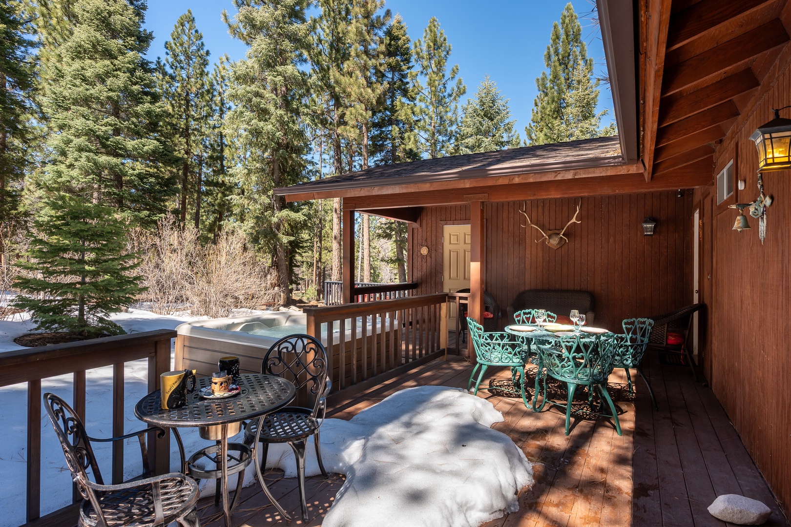 Cozy mountain cabin nestled among towering pines, featuring outdoor seating and a hot tub for soaking up the fresh alpine air after a day of adventure.