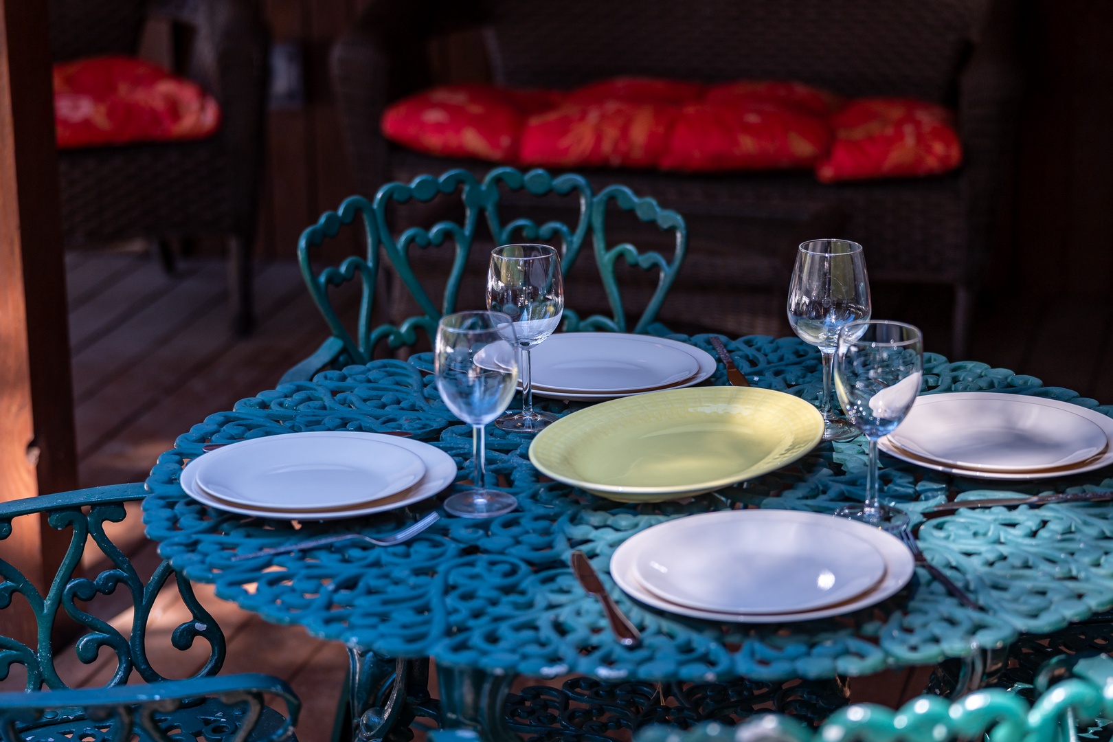 Your romantic dinner awaits at this charming turquoise table, complete with elegant place settings and wine glasses for intimate evenings.