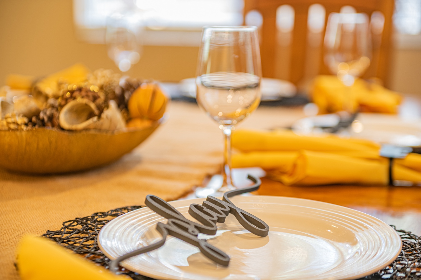 An elegantly set dining table awaits you, with gleaming glassware, decorative accents, and warm golden tones creating an inviting atmosphere for your meals.