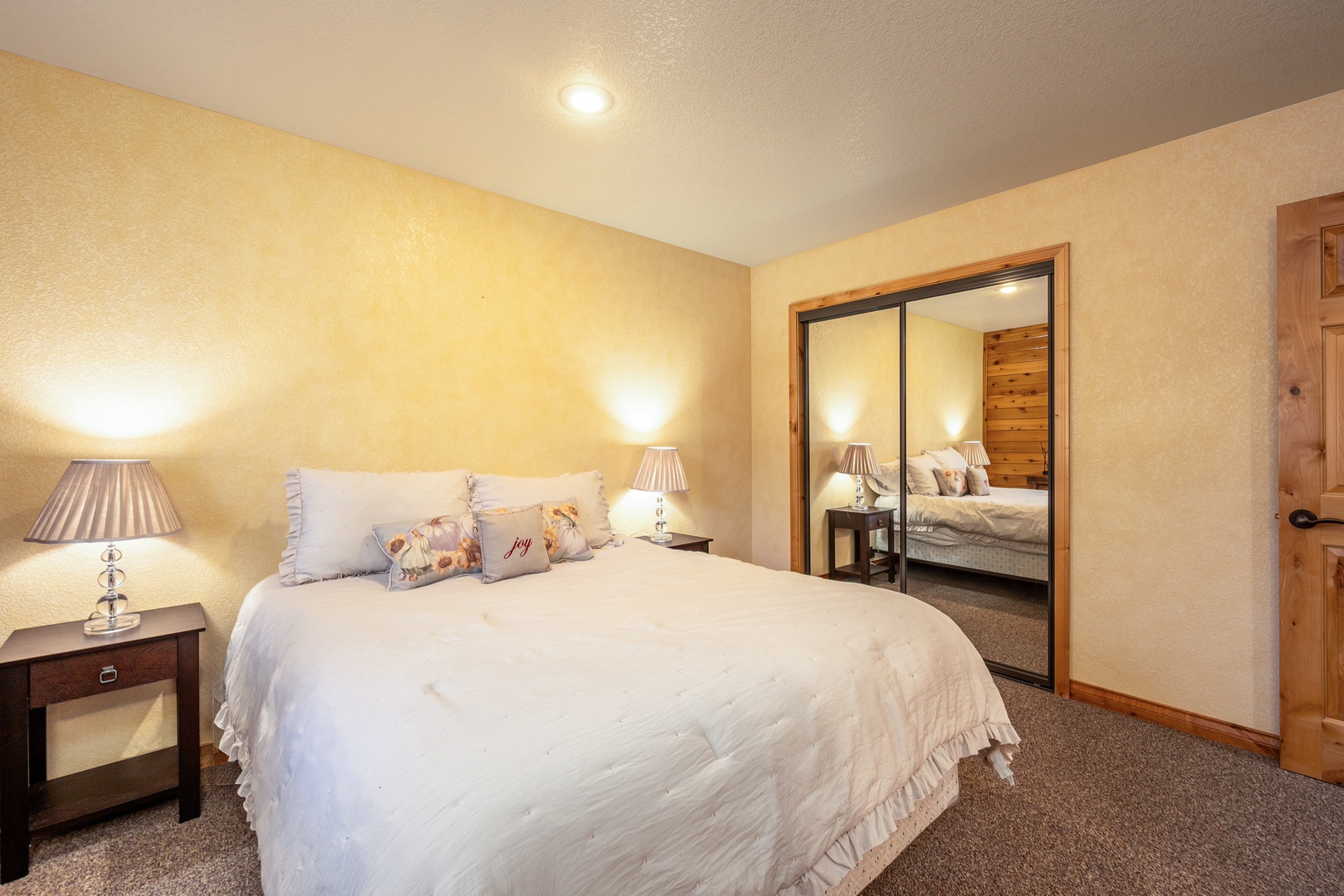 Sink into crisp white linens and enjoy warm ambient lighting in your cozy bedroom with mirrored wardrobe storage.