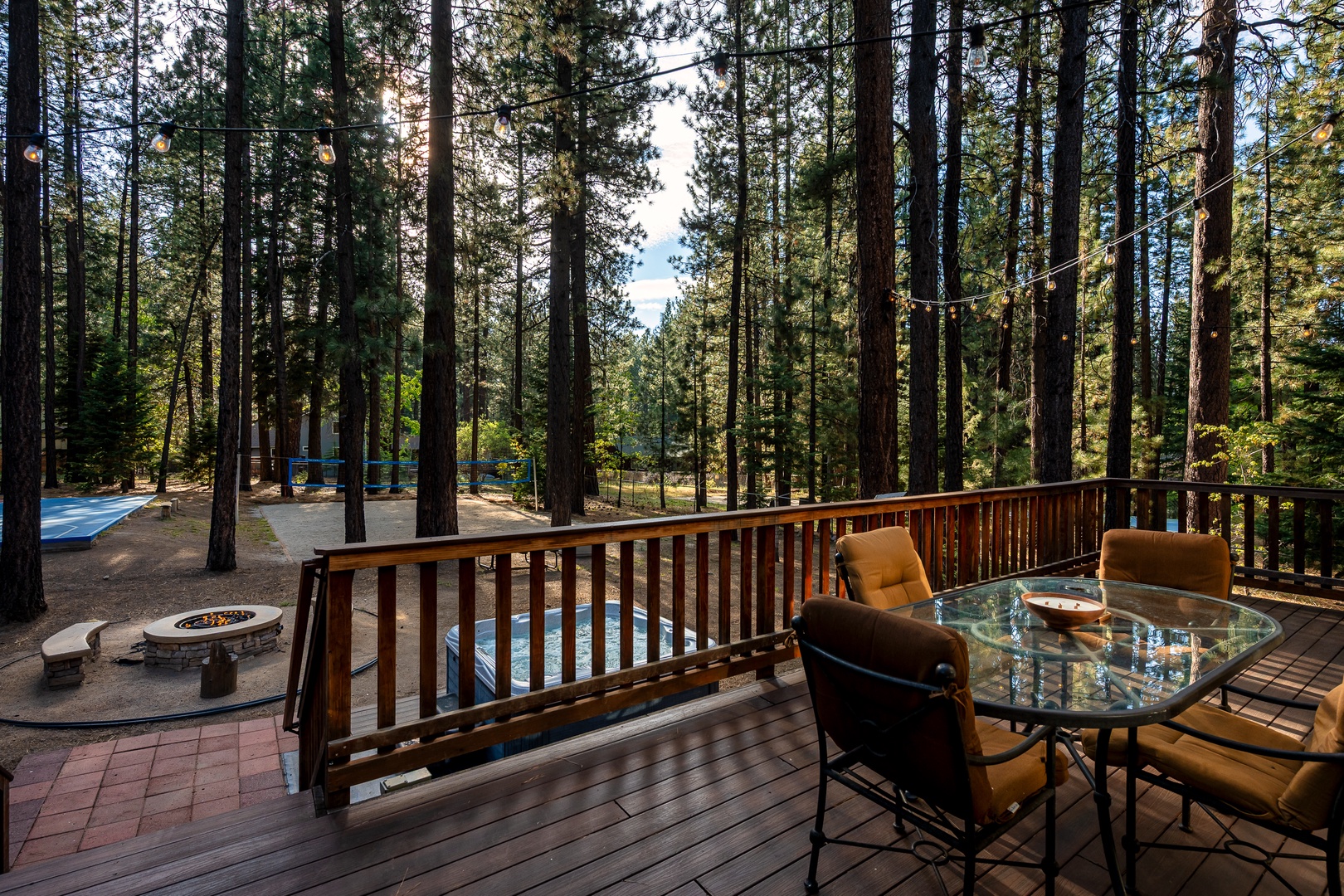 Sip your morning coffee on this spacious deck surrounded by towering pines, where sunlight filters through the trees and a cozy fire pit awaits your evening gatherings.