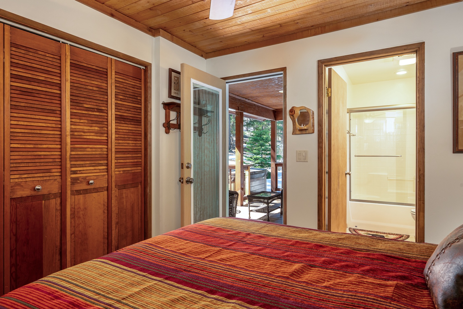 Relax in this inviting bedroom with warm wood accents, vaulted pine ceilings, and direct access to your private outdoor patio, where mountain breezes await your morning coffee.
