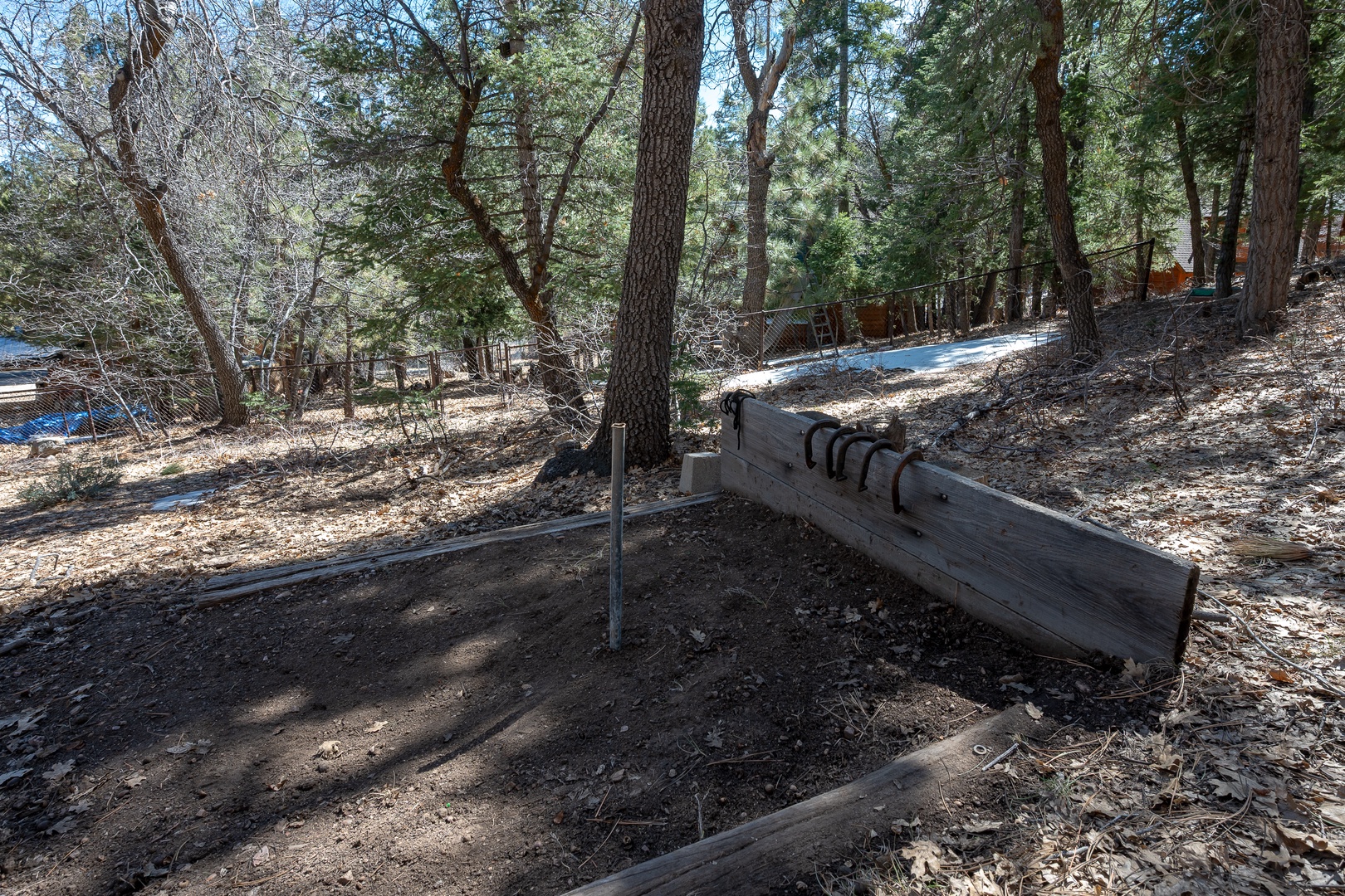 Rustic horseshoe pit nestled among towering pines creates the perfect spot for friendly competition during your mountain retreat.