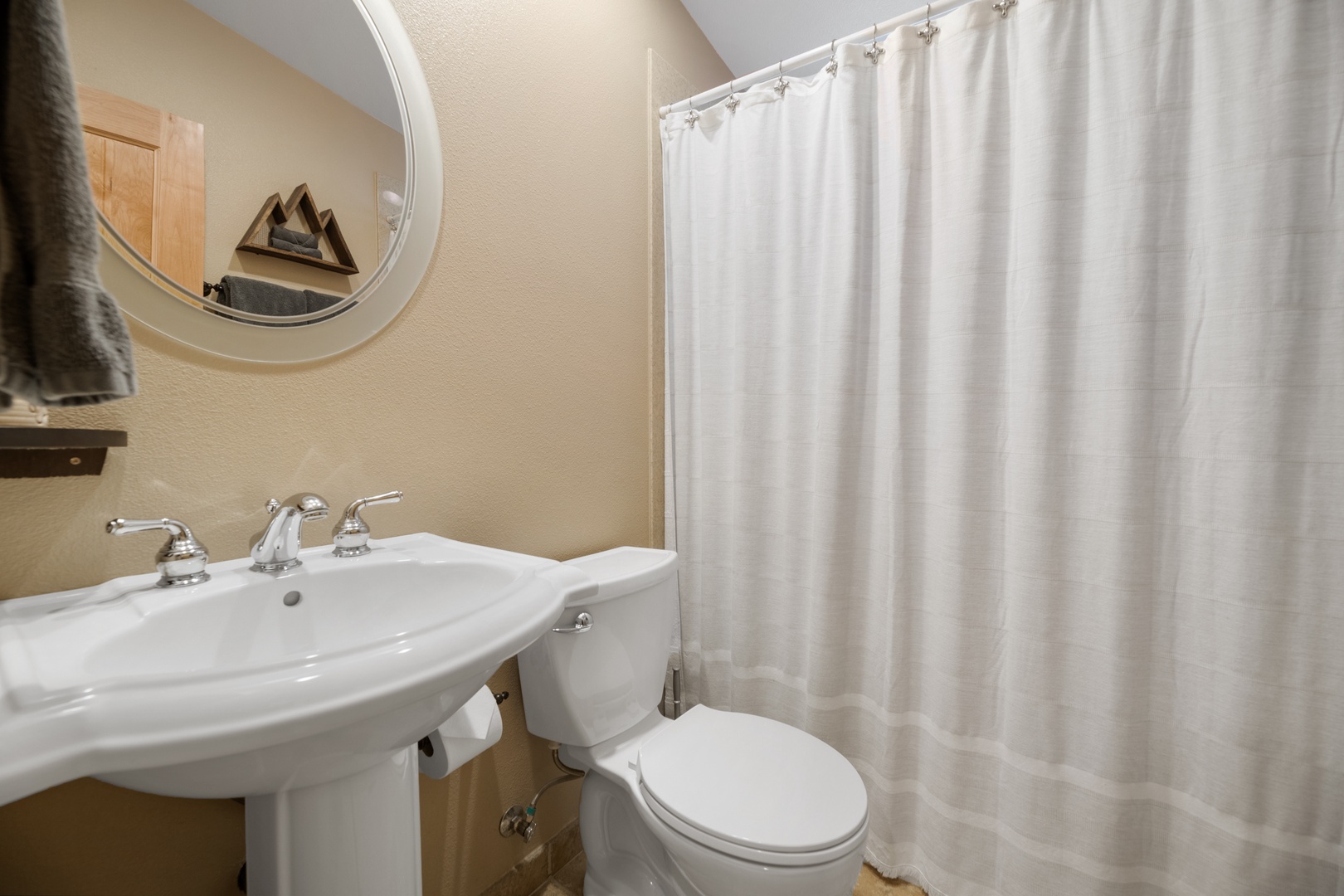 Your private bathroom features a pedestal sink, toilet, and shower, all dressed in crisp, clean finishes for a refreshing and comfortable stay.