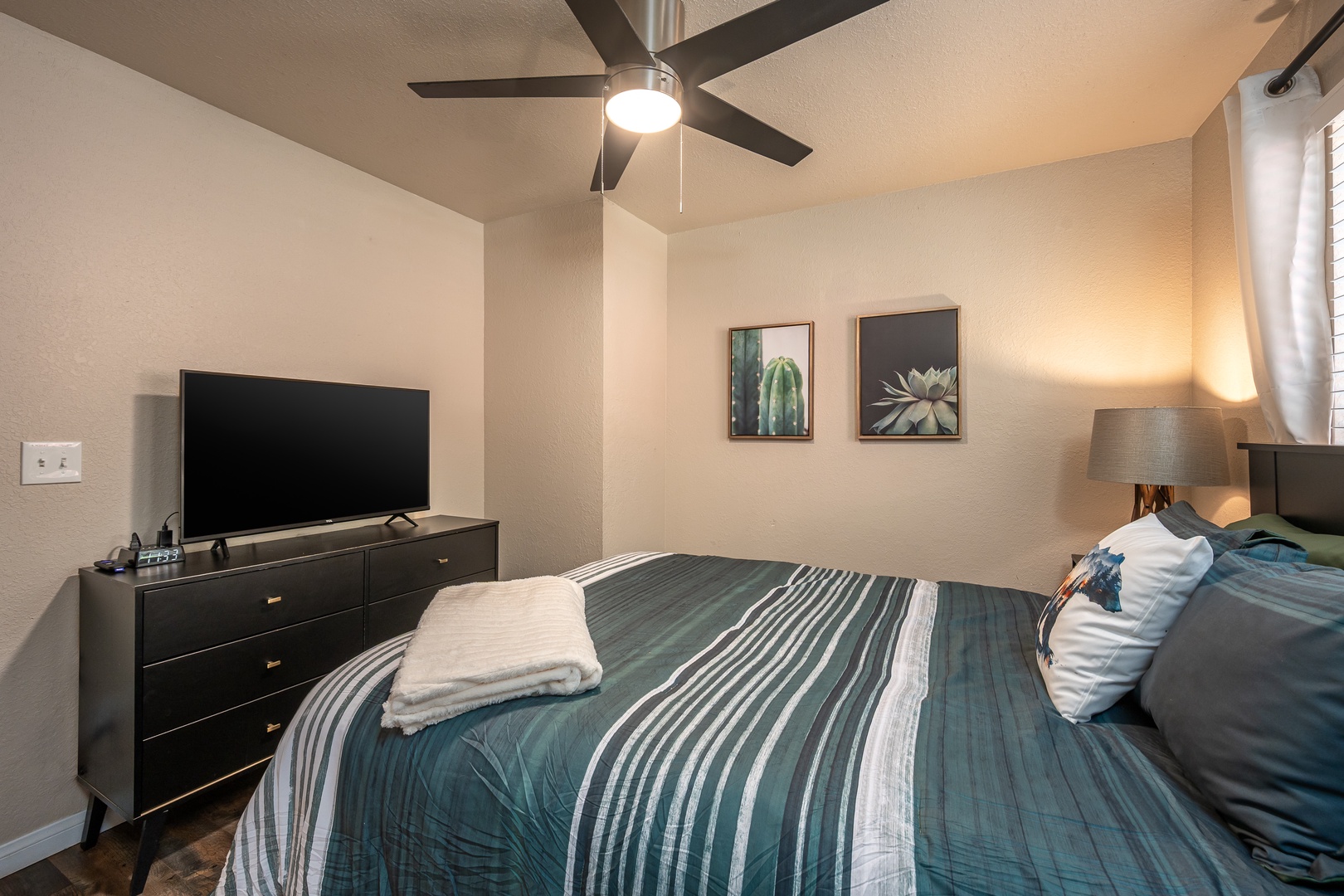 Unwind in your cozy bedroom, where soft linens, modern décor, and a ceiling fan ensure your comfort after a day of exploring.
