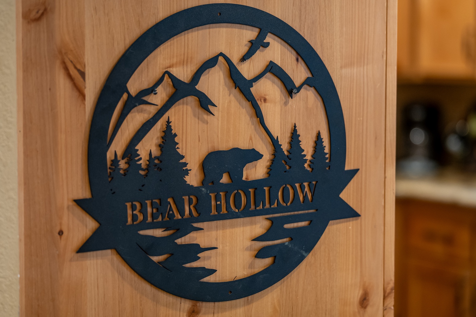 Bear Hollow welcomes you with its mountain-inspired charm, featuring pine trees, majestic peaks, and a bear silhouette beneath a soaring eagle.