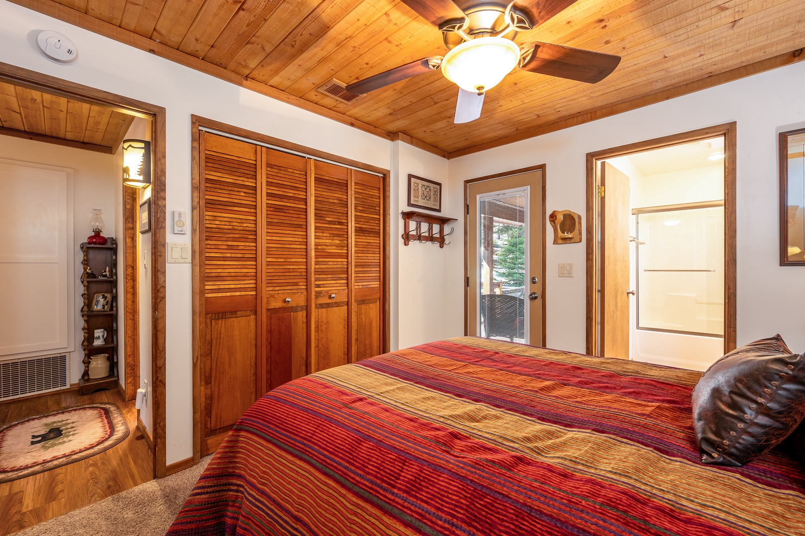 Cozy cabin bedroom with warm wood ceilings, built-in storage, and colorful southwestern bedding welcomes you to mountain retreat comfort.