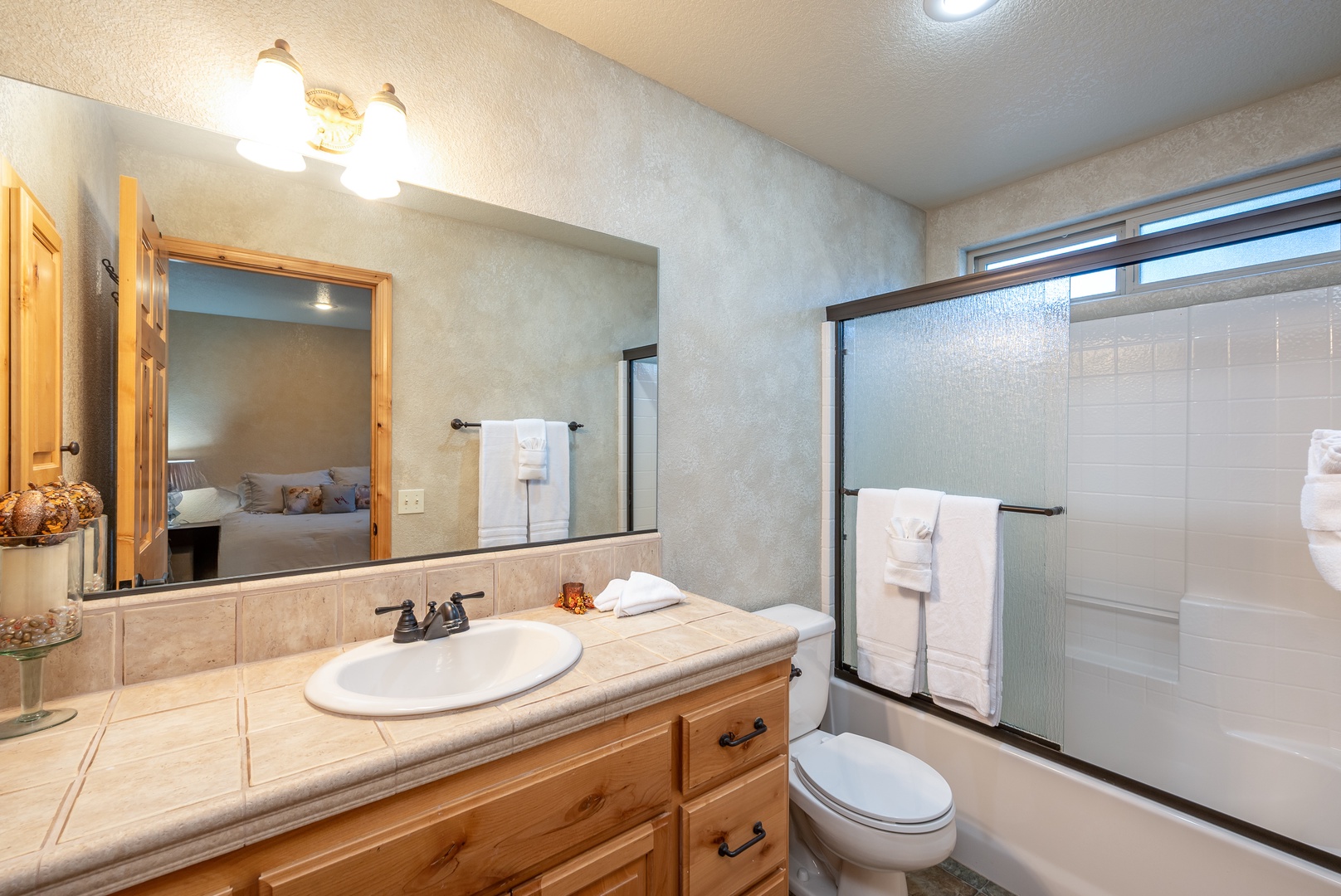 Freshen up in your private bathroom featuring warm wood vanity, spacious shower, and fluffy towels awaiting your arrival.