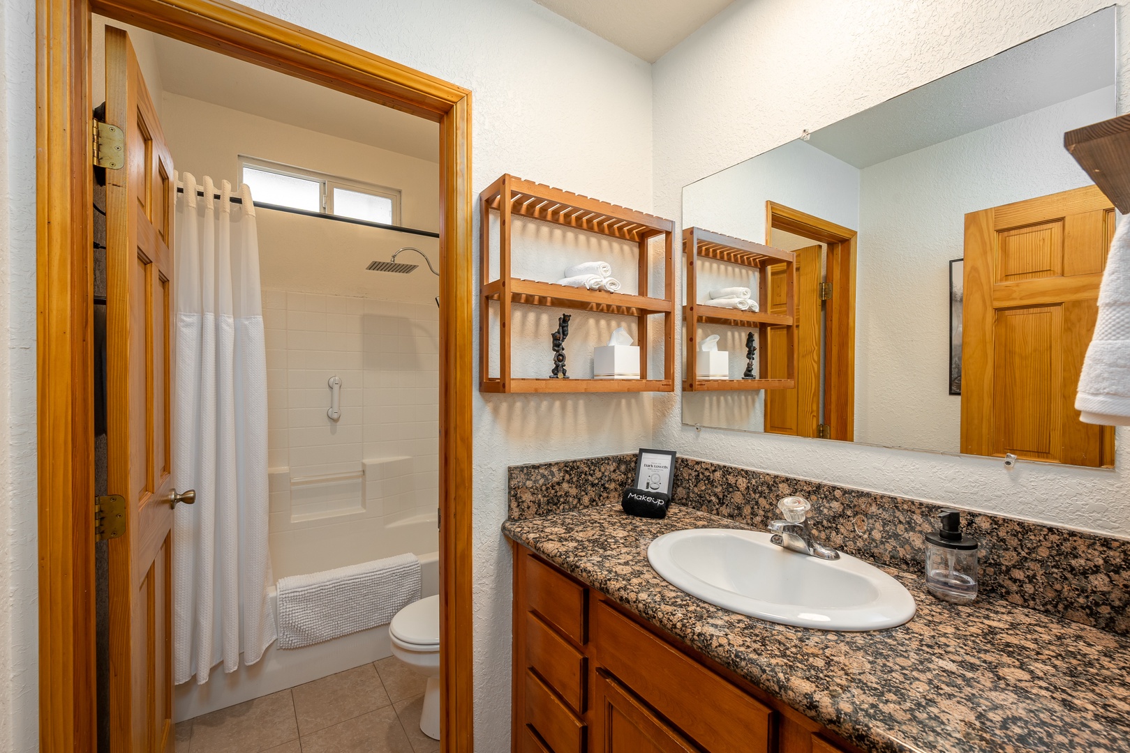 Your private bathroom features a tub-shower combo, granite vanity, and thoughtfully stocked shelves with fresh towels and essentials for a comfortable, hassle-free stay.