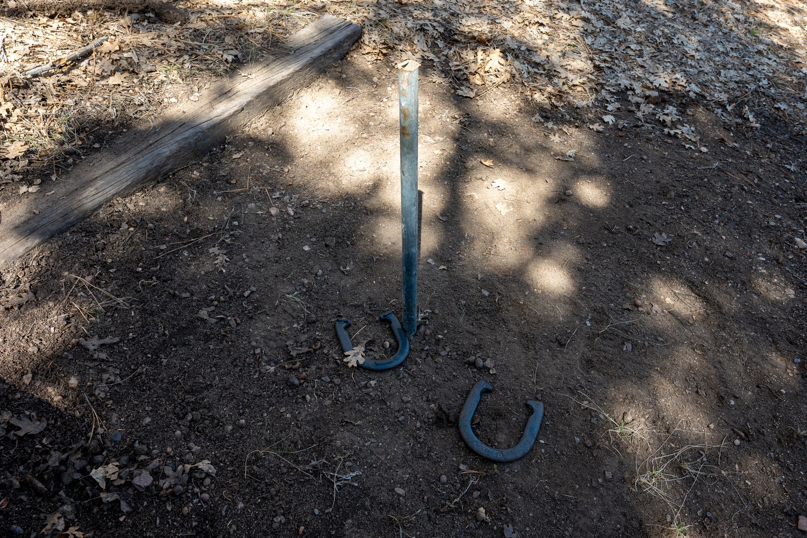 Outdoor game area with horseshoe pit and wooden benches for your enjoyment.