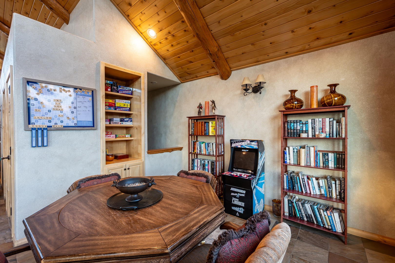 Unwind in your cozy game room with arcade fun, board games, and endless books under rustic wooden beams.