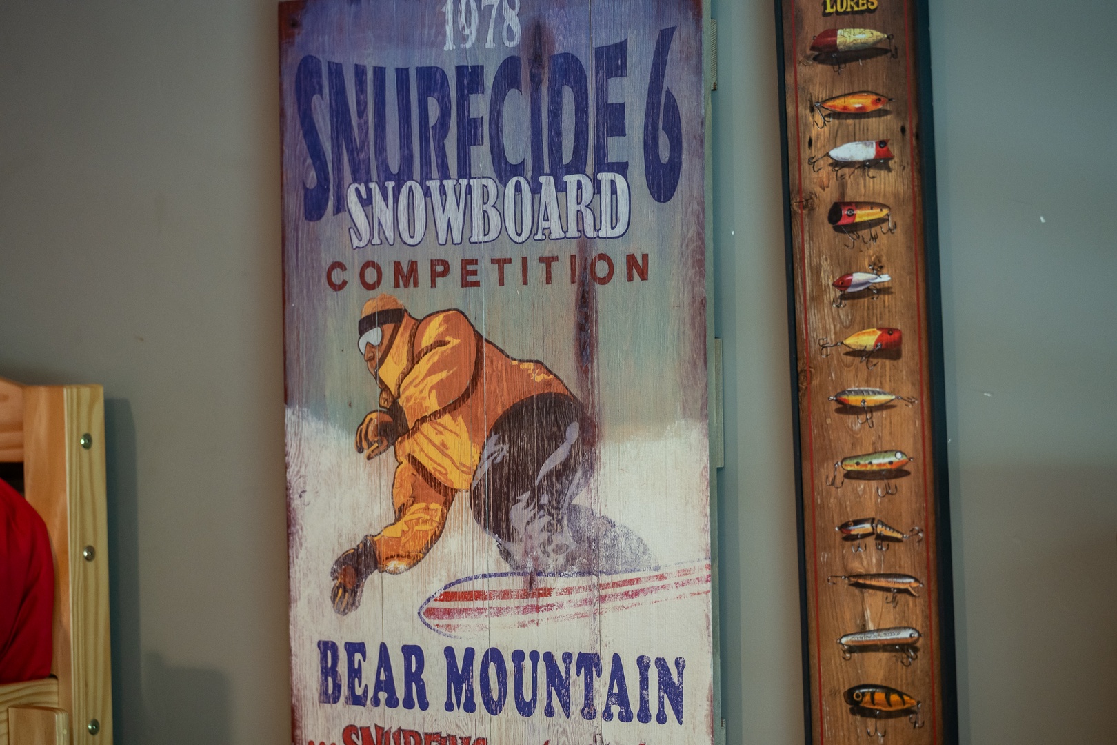 Vintage ski lodge charm adorns the walls, featuring retro snowboarding memorabilia and classic fishing lures that celebrate mountain adventures and outdoor heritage.