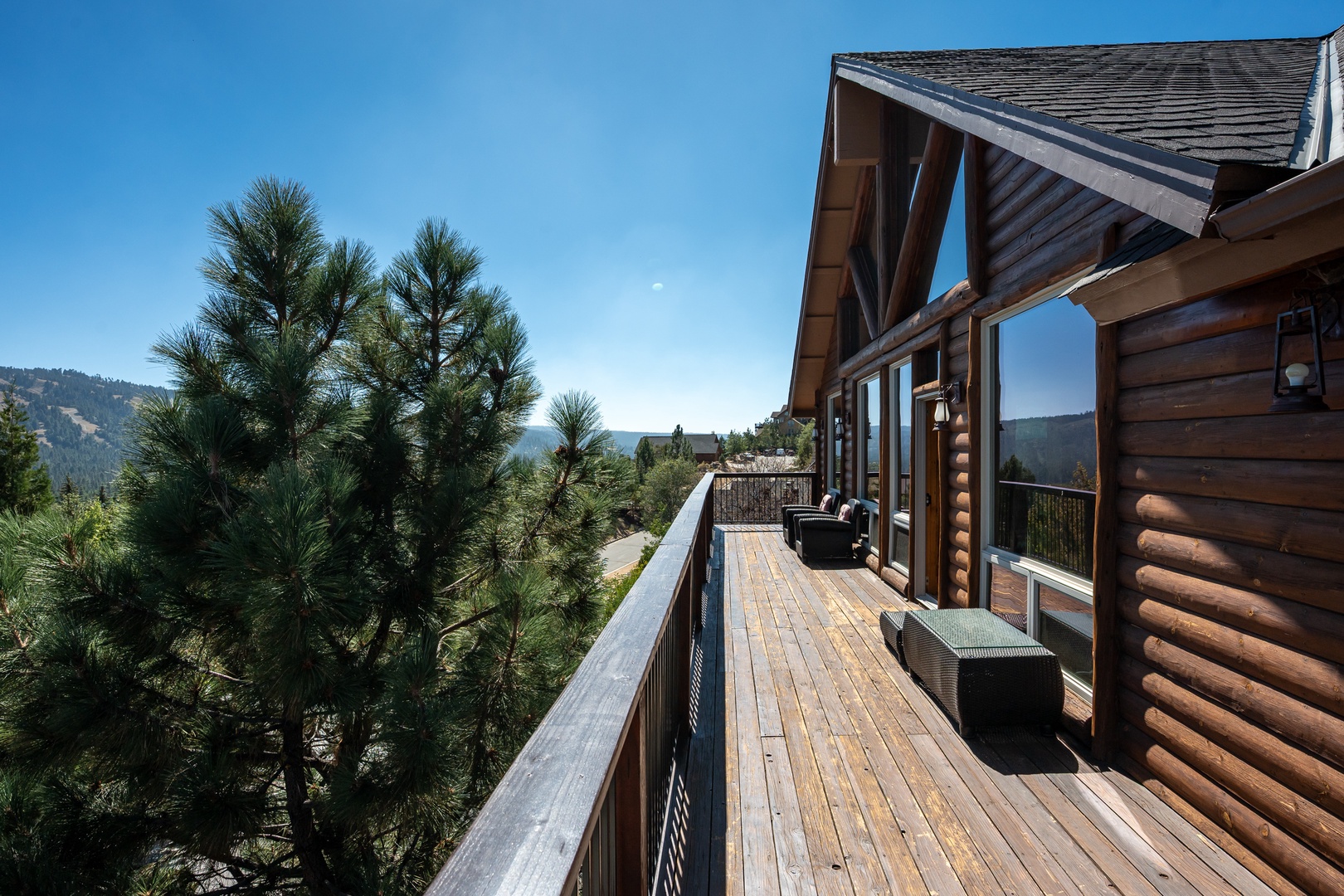Your private deck wraps around this handsome log cabin, offering cozy seating and sweeping mountain vistas that stretch beyond the pines—a perfect spot to sip morning coffee or unwind at day's end.