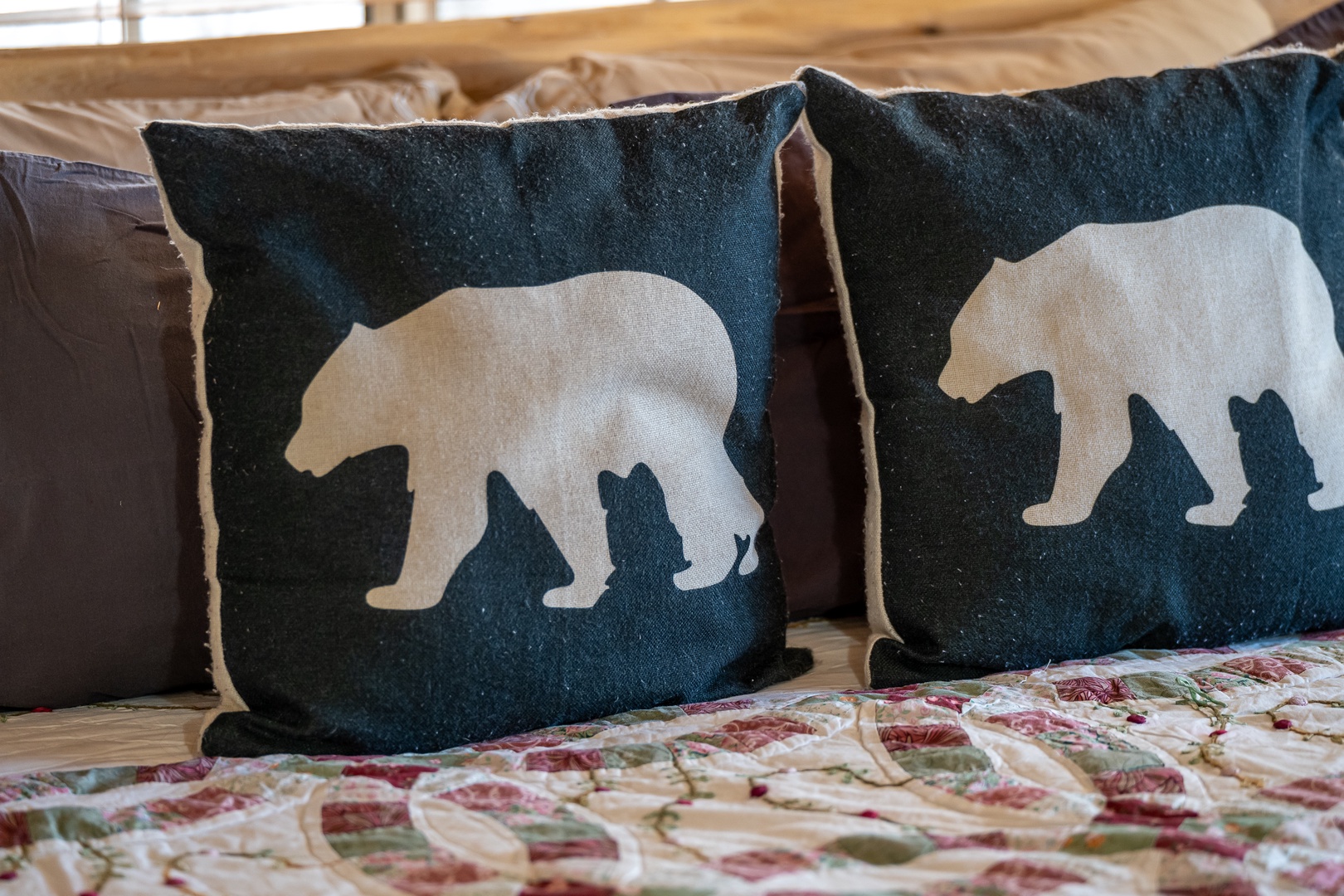 Cozy bear-themed pillows await you on your comfortable bed, creating a charming wilderness retreat atmosphere for peaceful nights.