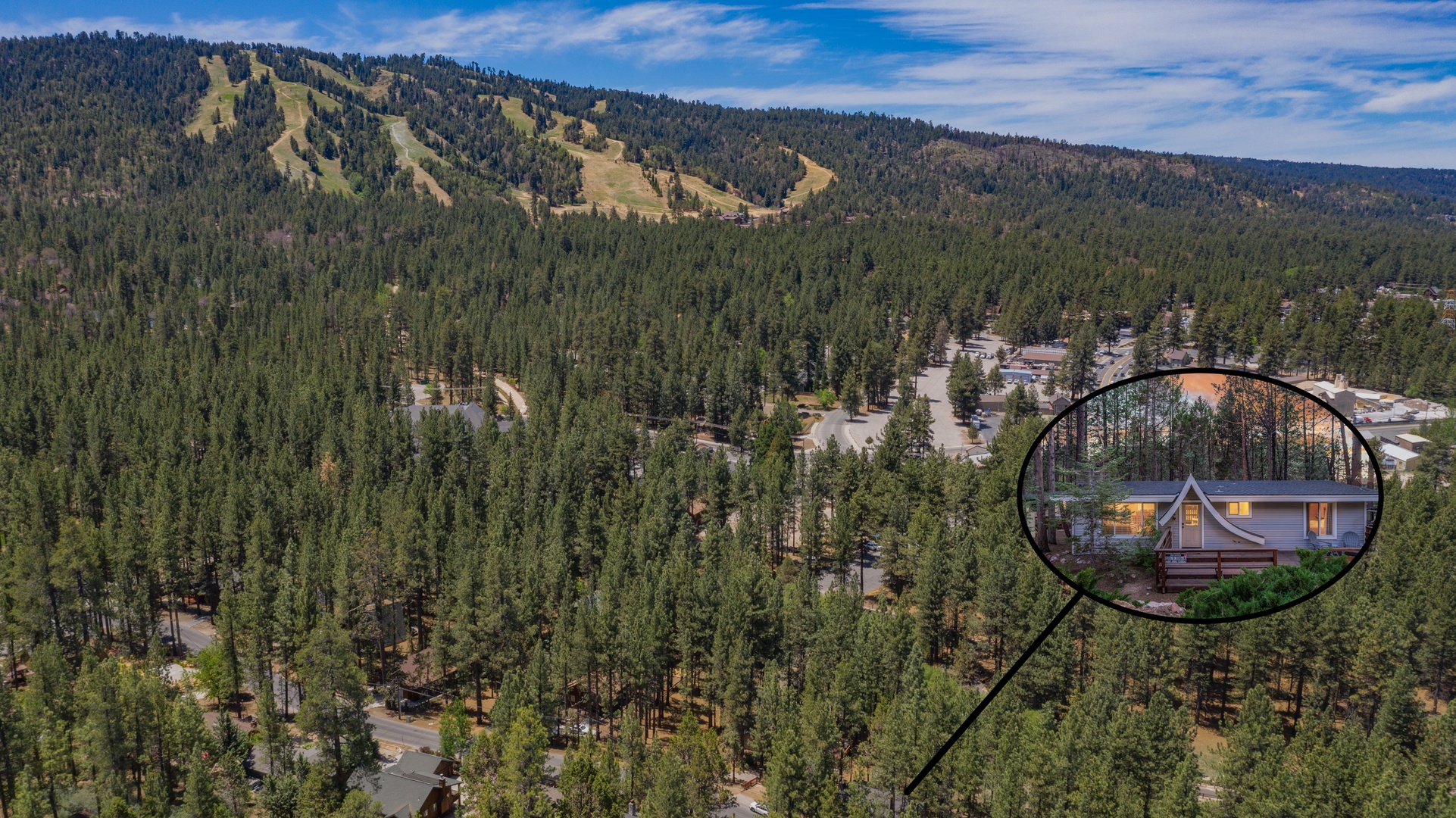 Aerial view of the property nestled in a forested mountain setting, with ski slopes visible in the distance and easy access to outdoor recreation.