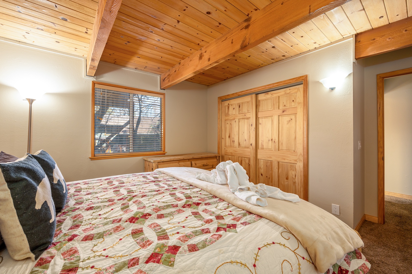 Cozy bedroom with exposed wood beams and rustic charm where you'll wake up refreshed in mountain comfort.