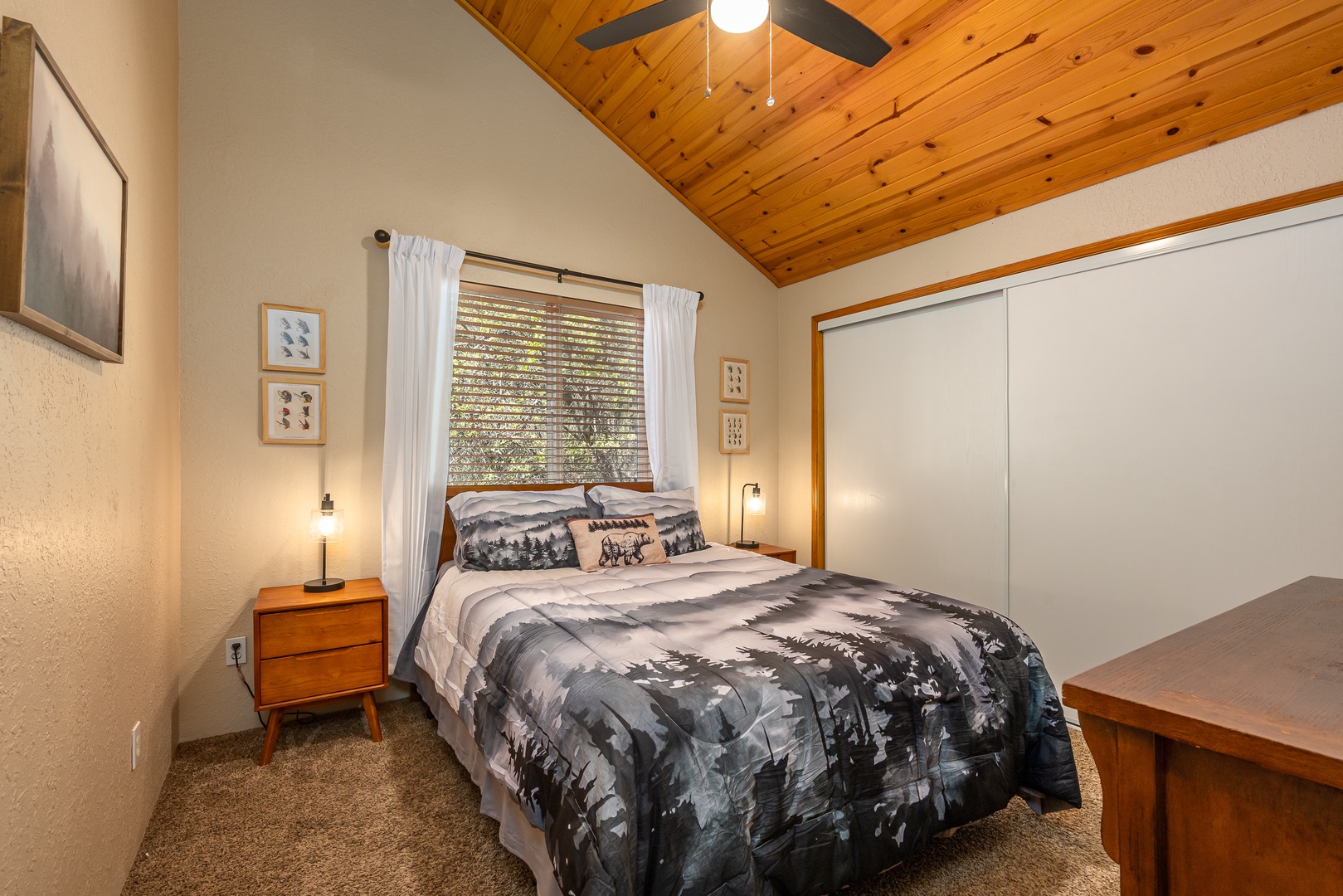Drift off under warm wood-paneled ceilings while natural light filters through your window. Your private retreat features a plush bed, mid-century nightstand, and ample closet space for a cozy mountain escape.