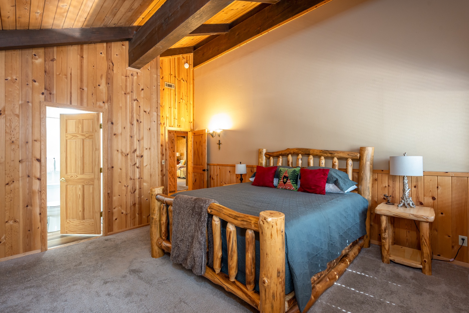 Sink into your plush bed framed by handcrafted rustic wood beneath soaring vaulted ceilings with warm timber beams, creating a cozy mountain retreat for restful nights.