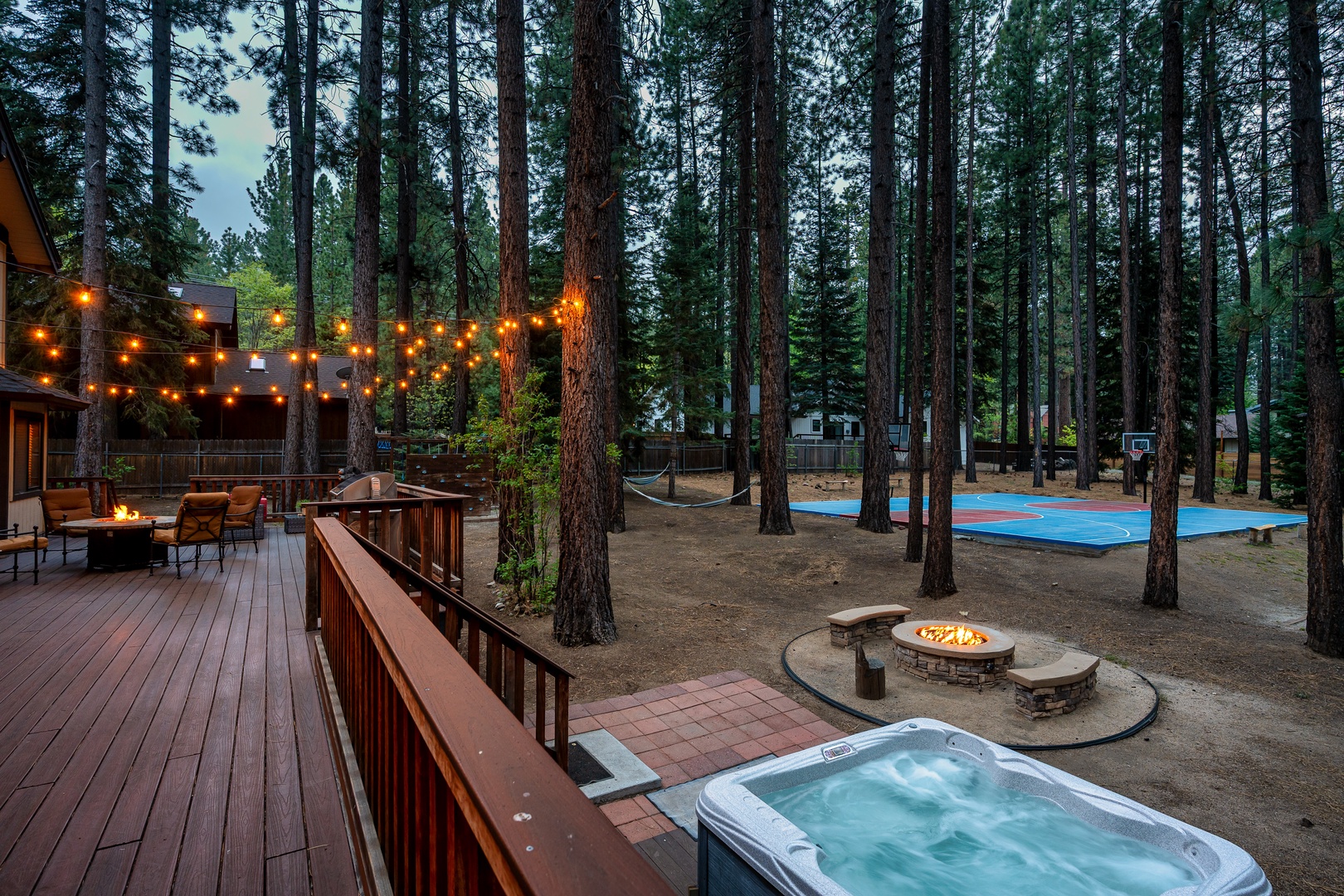 Nestled among towering pines, the backyard features a hot tub, fire pit, hammock, and basketball court—your private retreat for cozy evenings and outdoor fun.