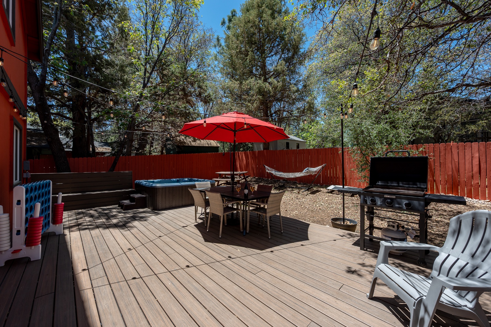 Relax in your private backyard oasis with hot tub, shaded dining, BBQ grill, and hammock under towering pines—perfect for unwinding or gathering outdoors.