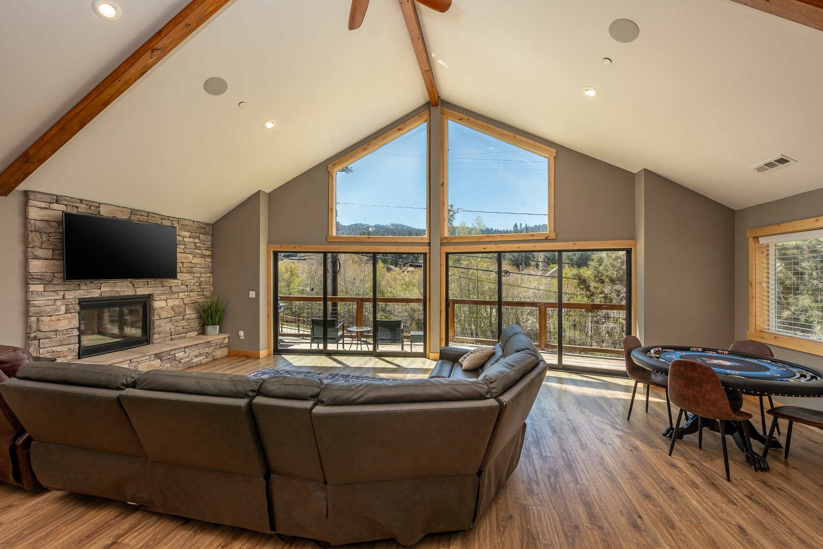 Picture yourself unwinding on the plush sectional, warmed by the stone fireplace, as sunlight streams through towering windows that frame peaceful forest views beyond your private deck.