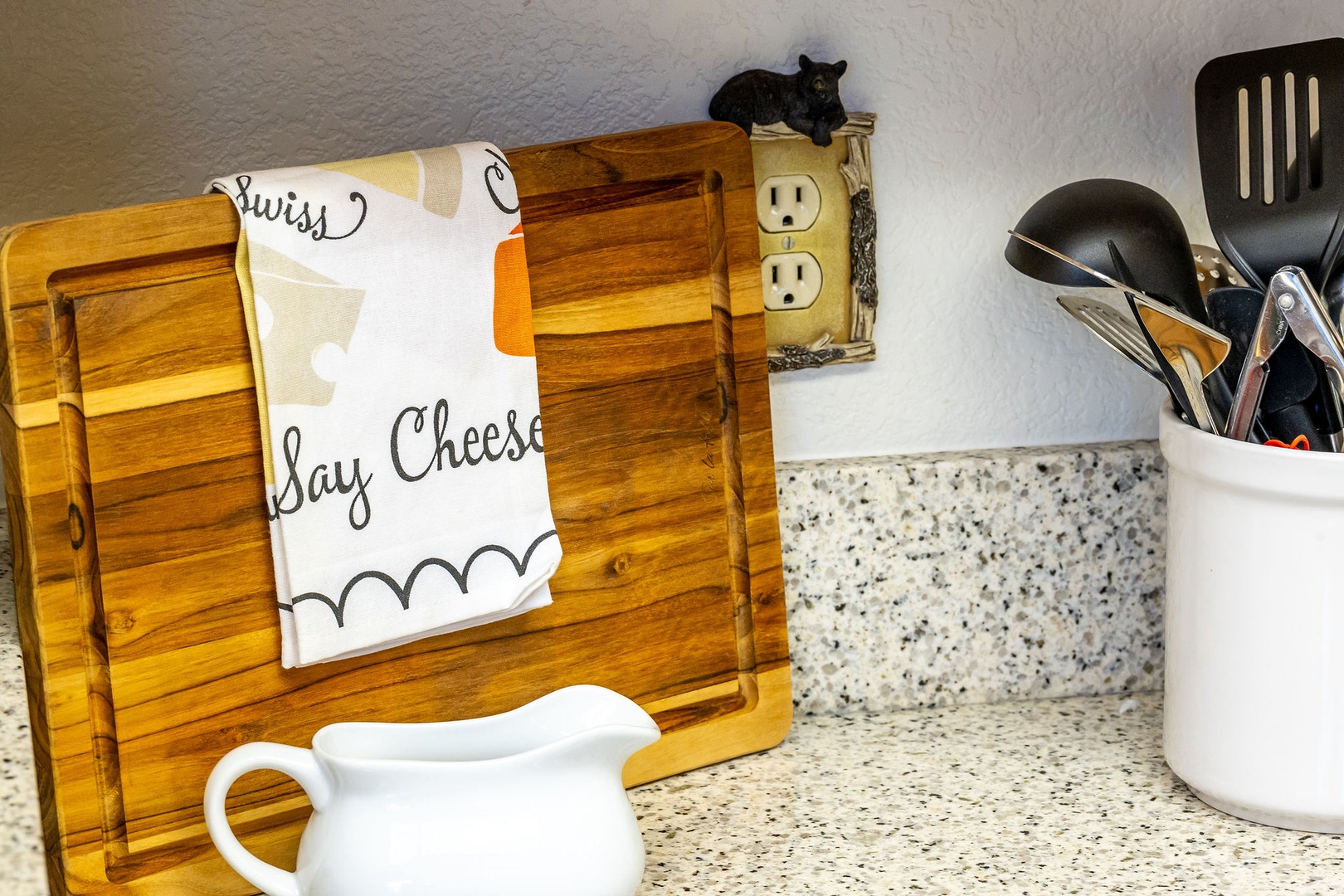 Your well-equipped kitchen features granite countertops, quality cooking utensils, and charming touches like a wooden cutting board holder and cheerful dish towels.