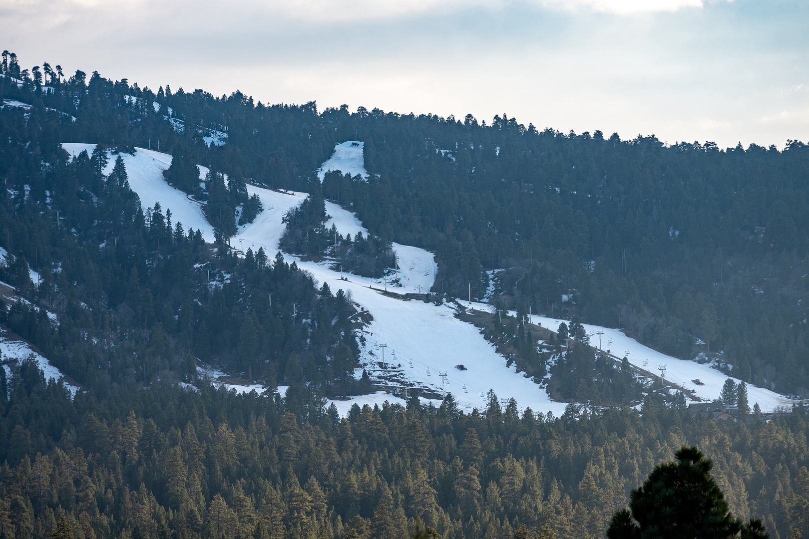 Snow-covered ski slopes wind through forested mountains, offering winter sports enthusiasts pristine runs and scenic alpine terrain.