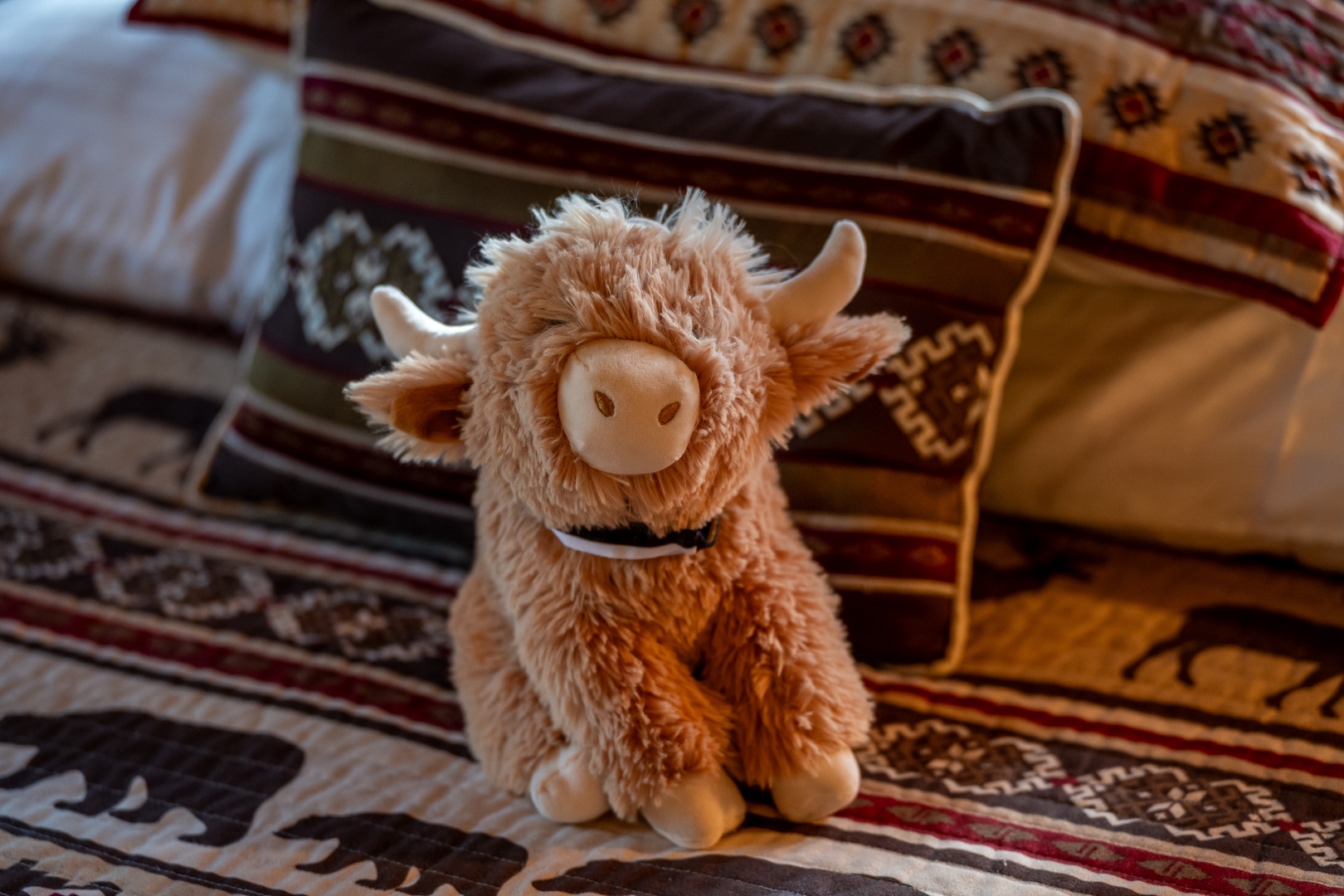 A friendly plush companion waits to greet you, perched on warm, inviting textiles that add charm and comfort to your home away from home.