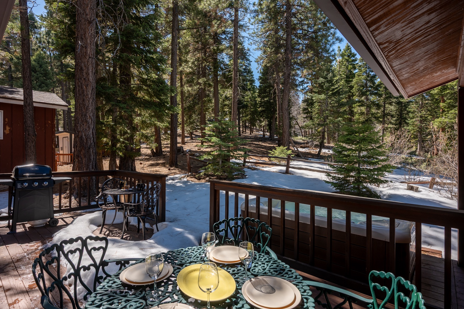 Towering pines frame this peaceful forest setting, where sunlight filters through evergreens to create a serene alpine backdrop for the property. Seasonal snow accents the natural landscape.