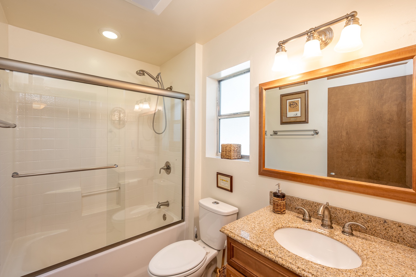 Step into your private bathroom featuring a spacious granite vanity, elegant mirror, and glass-enclosed tub-shower combo for refreshing moments.