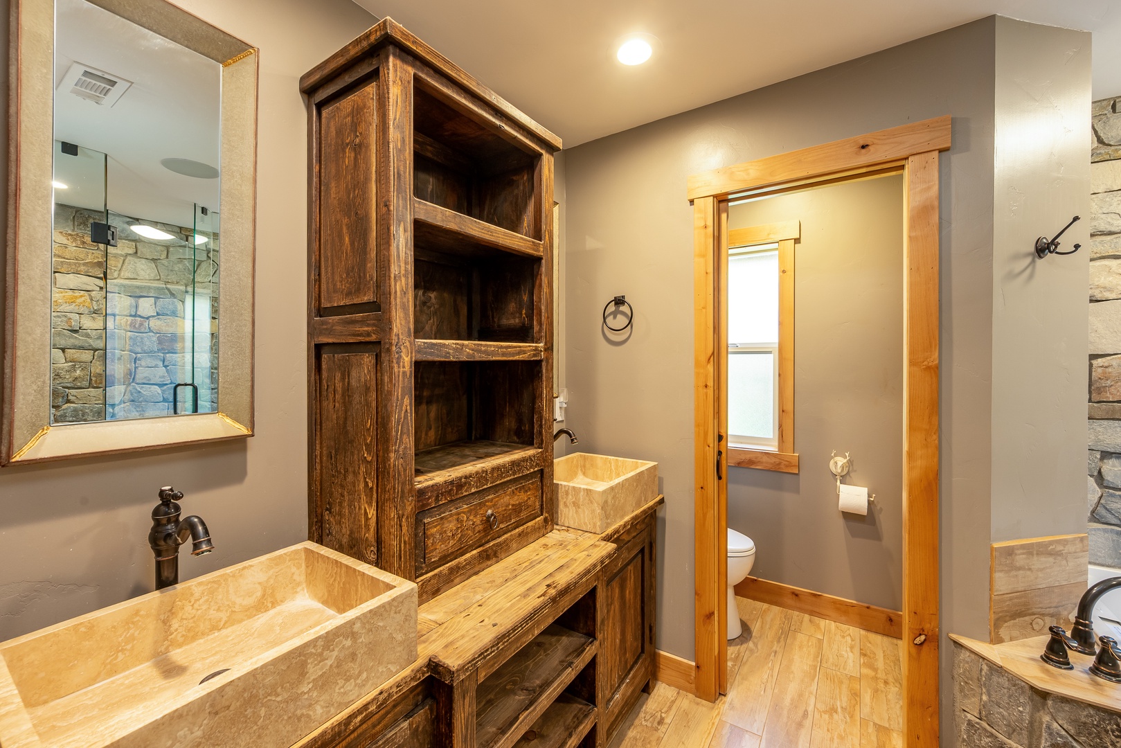 Step into this rustic-luxe bathroom, where handcrafted wood shelving meets sleek stone vessel sinks. Warm lighting and natural textures create a spa-like retreat after your mountain adventures.