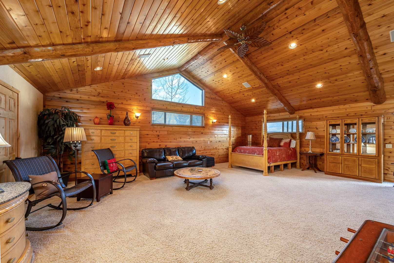 Unwind in this expansive log cabin loft with vaulted ceilings, cozy leather seating, and rustic four-poster bed creating your perfect mountain retreat.