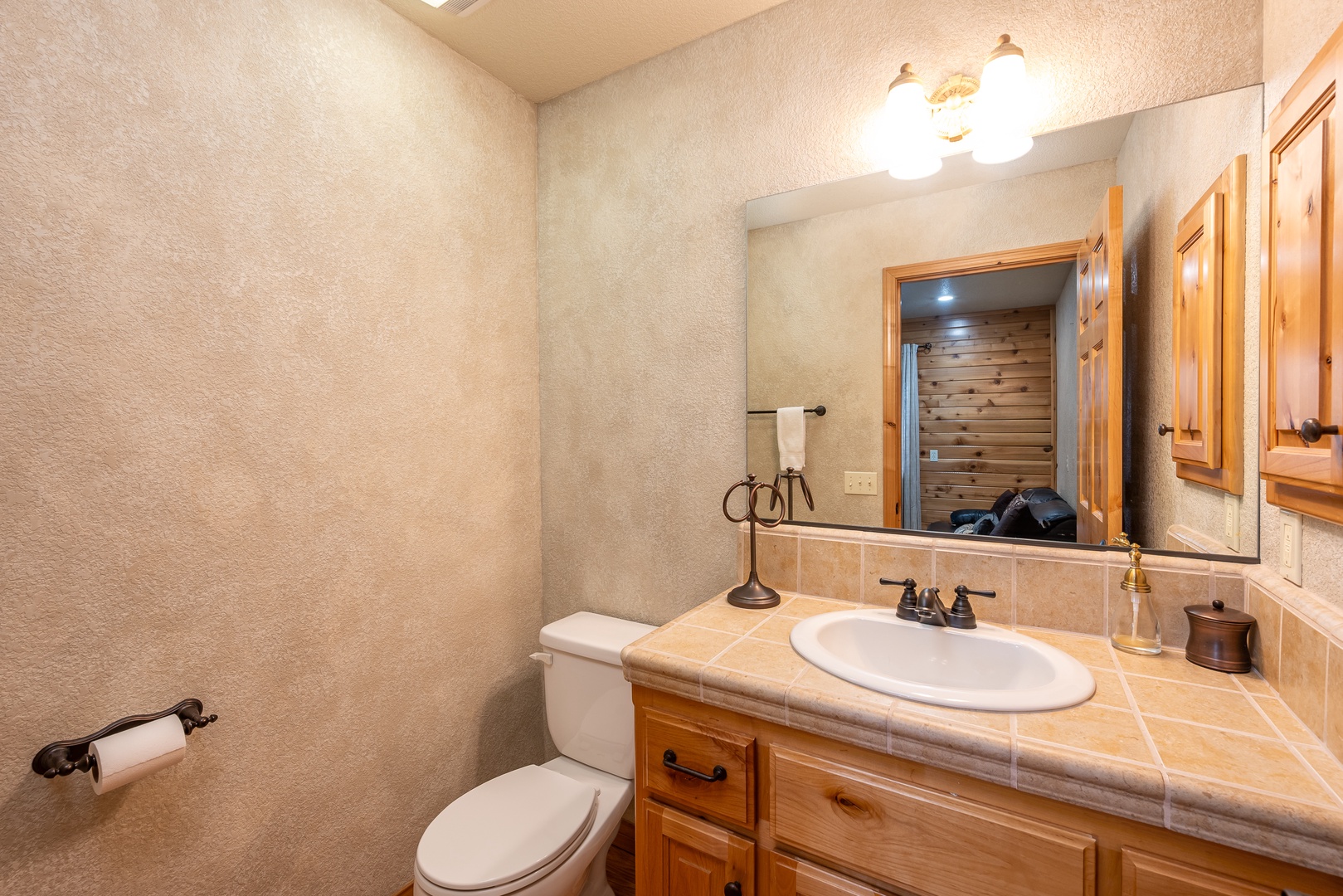 Your private powder room features warm tile countertops and rustic wood cabinetry for convenient guest refreshment.