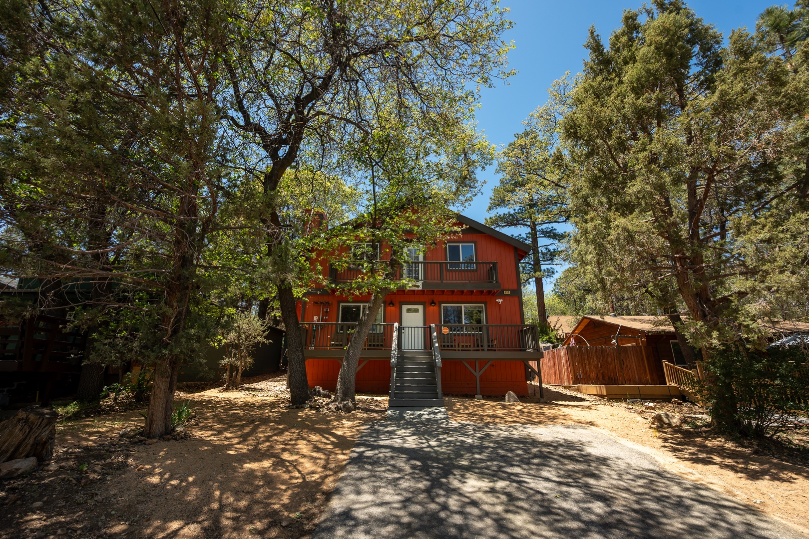 Charming red mountain cabin nestled among towering pines, offering peaceful seclusion and authentic alpine character with multiple levels of outdoor deck space for enjoying the fresh air.