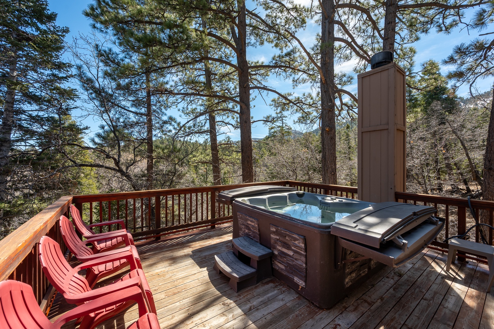 Soak in your private hot tub surrounded by towering pines, where forest serenity meets pure relaxation on this elevated deck.