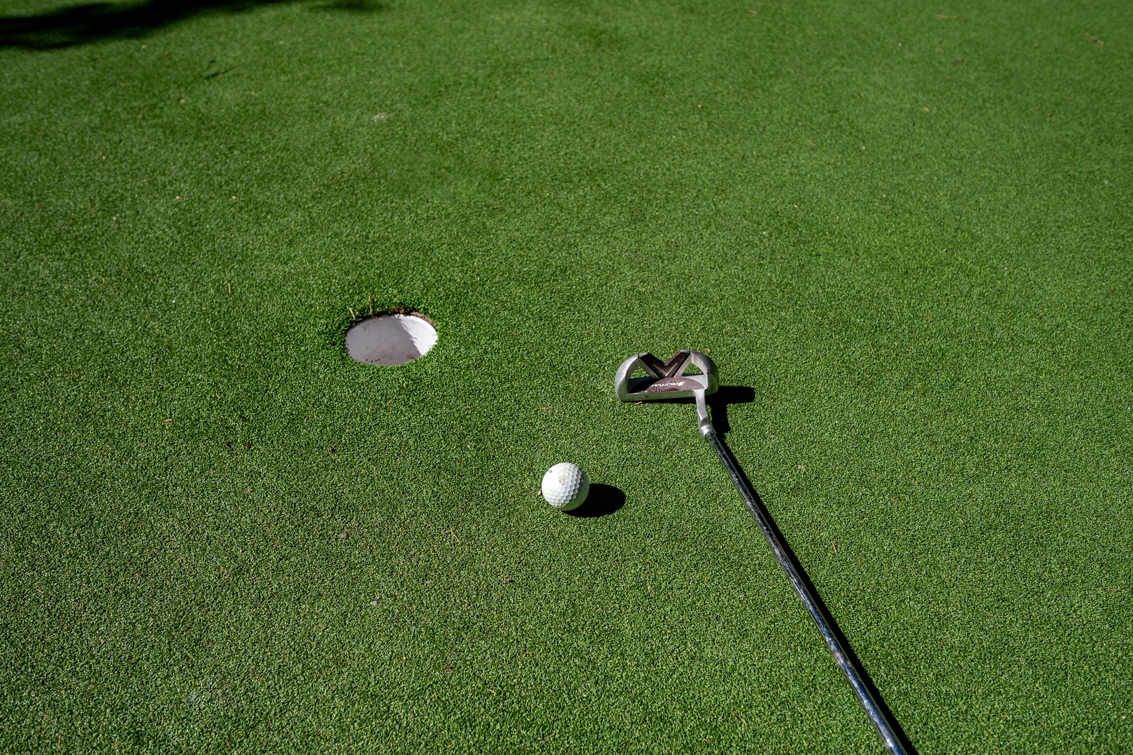 A putting green awaits your practice rounds, complete with pristine turf, flagged hole, and putter for perfecting your short game.