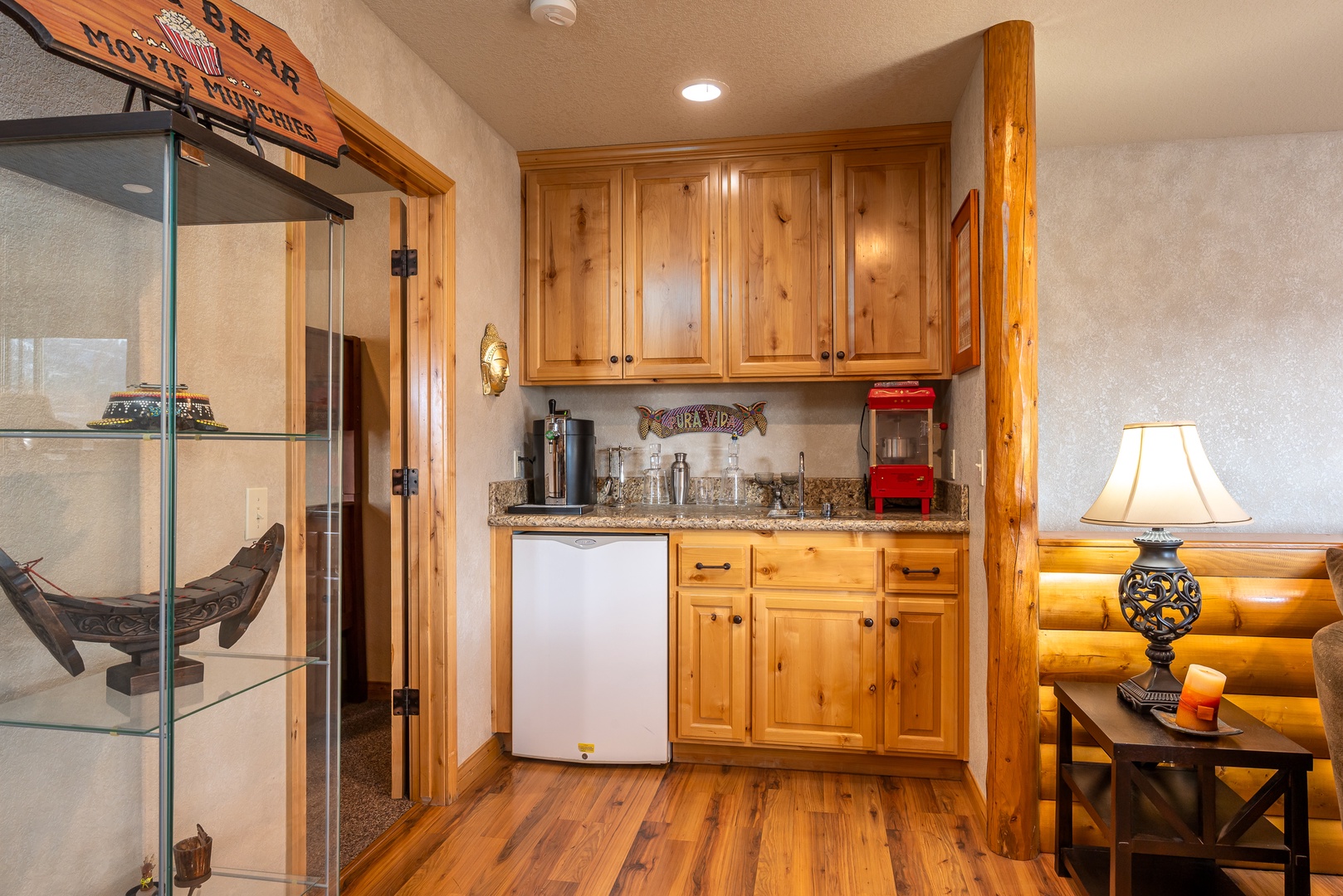 Your cozy kitchenette features warm wood cabinets, granite counters, and a charming display case showcasing rustic collectibles.