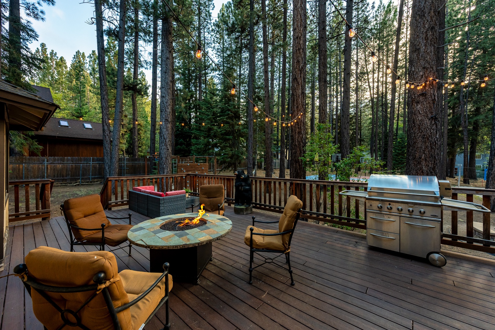 Gather around the glowing fire pit on your private deck, where string lights twinkle through towering pines. The hot tub bubbles nearby while the grill awaits your evening feast.