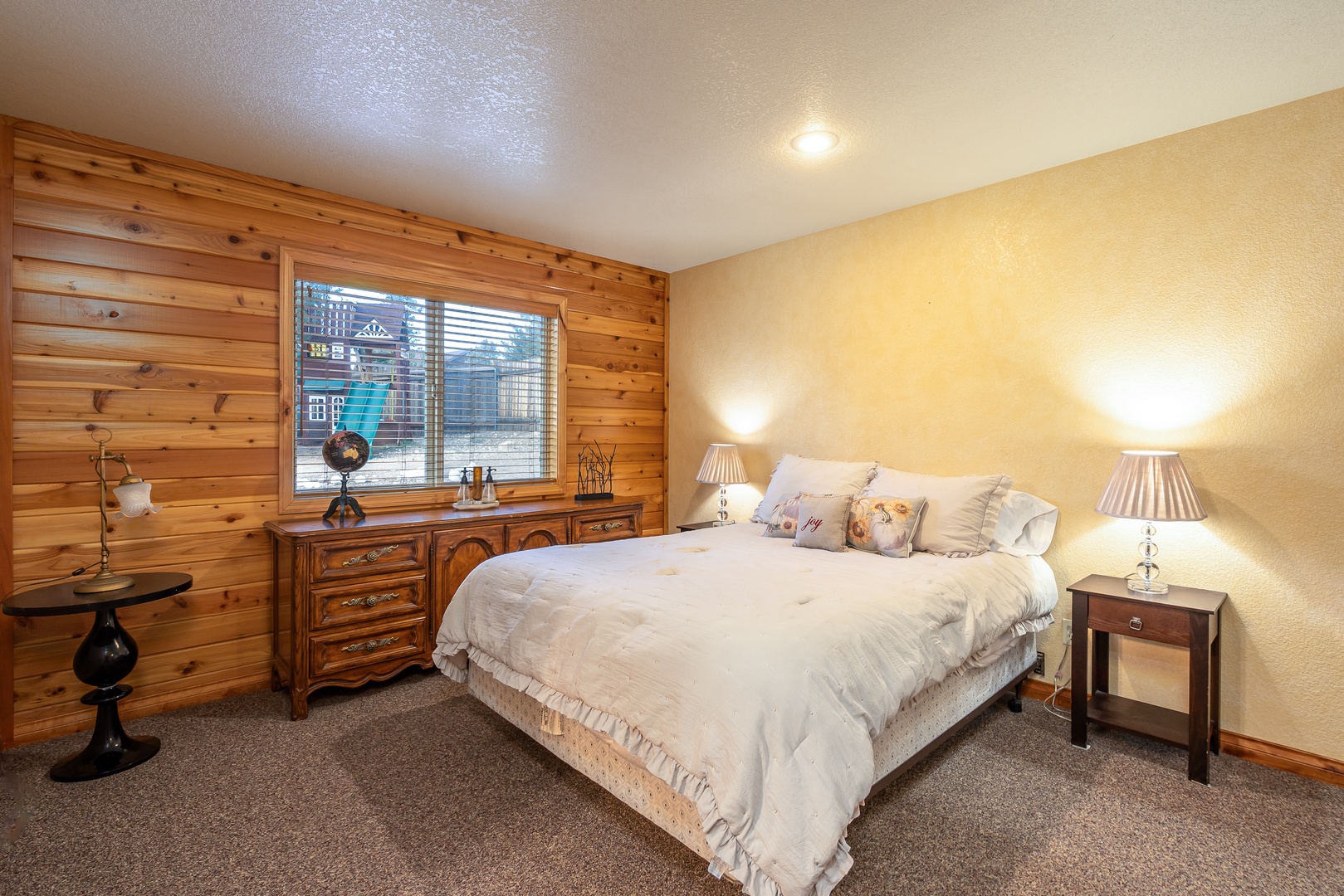 Drift off in your cozy bedroom featuring warm wood paneling, plush bedding, and bedside lamps creating the perfect ambiance for restful nights.