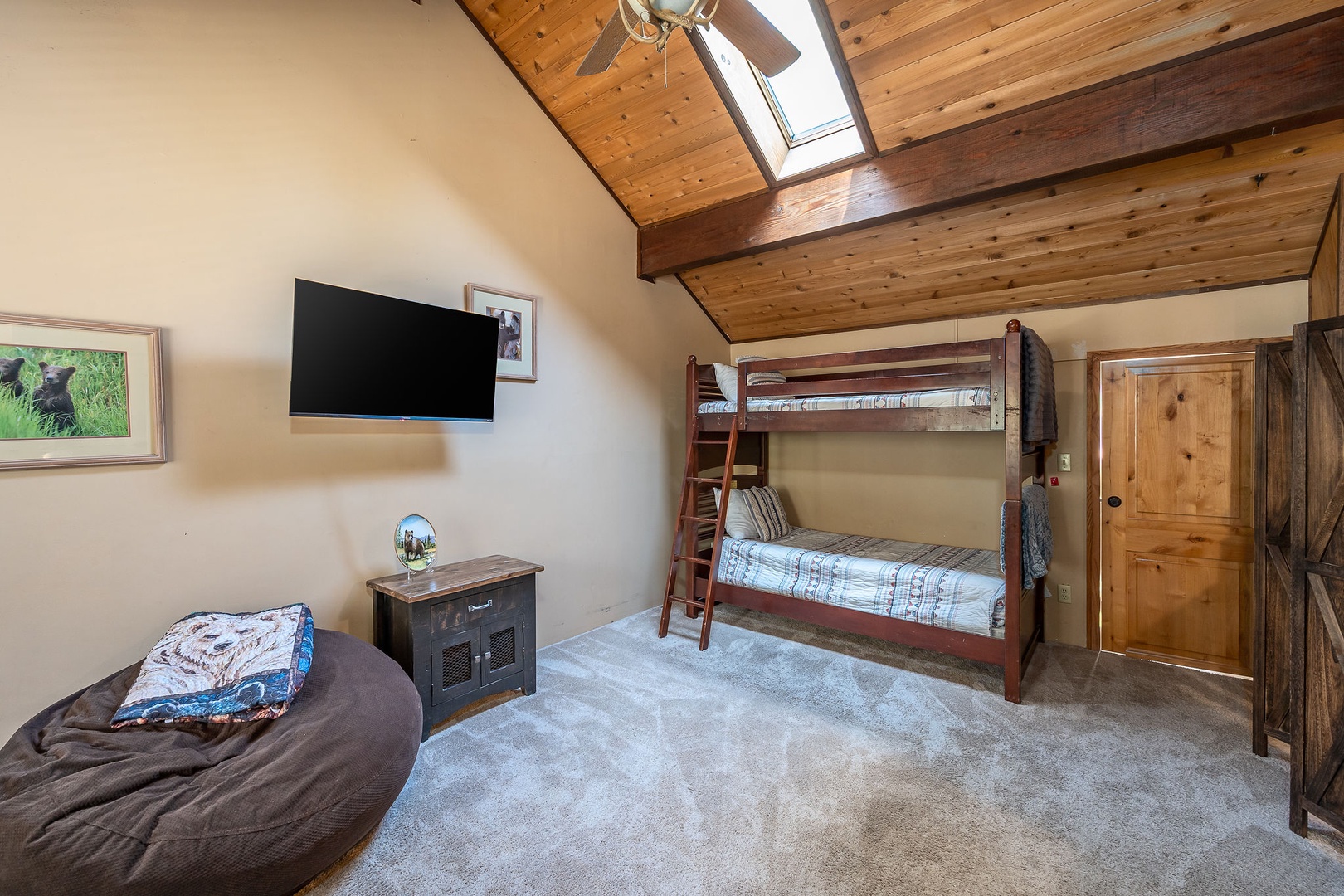 Cozy bedroom with warm wood-beam ceilings, natural skylight, and plush bunk beds perfect for kids or groups. Your mountain retreat features rustic charm with modern touches throughout.